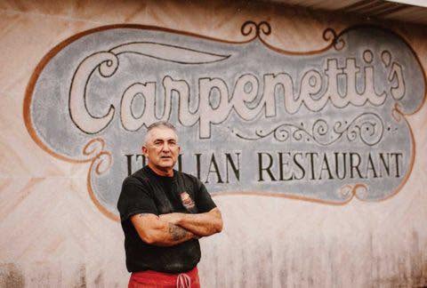 Carpenetti's owner in front of Italian Restaurant mural